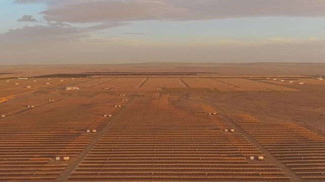 Solar photovoltaic panels at sunrise/sunset; wind turbine power plant; new energy