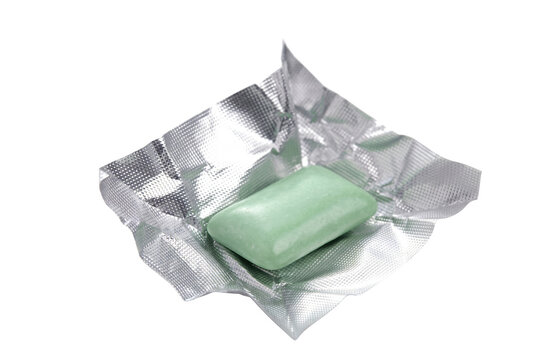 Green Peppermint Chewing Gum Pellet Resting on an Open Silver Foil Wrapper
