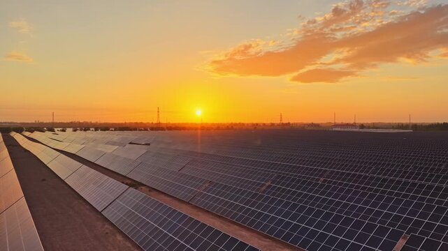 Solar photovoltaic panels at sunrise/sunset; wind turbine power plant; new energy