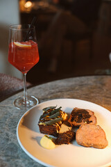 Red Spritz Cocktail with Dinner Plate at Restaurant © Maria Rasin