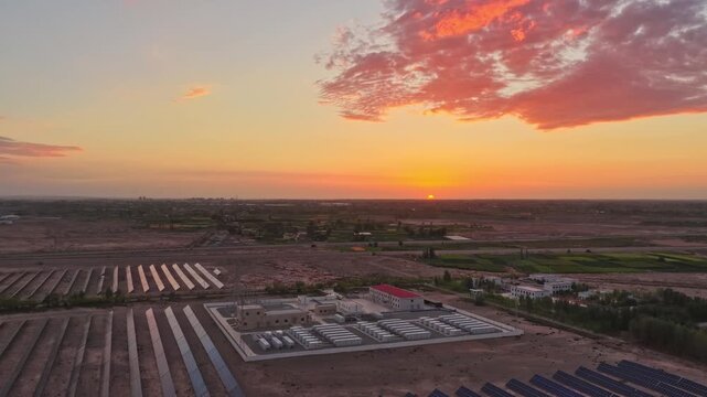 Solar photovoltaic panels at sunrise/sunset; wind turbine power plant; new energy