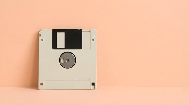 Vintage floppy disk placed on a soft peach background with empty space