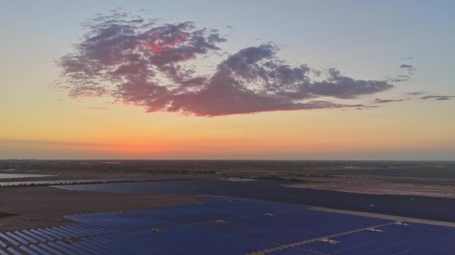 Solar photovoltaic panels at sunrise/sunset; wind turbine power plant; new energy