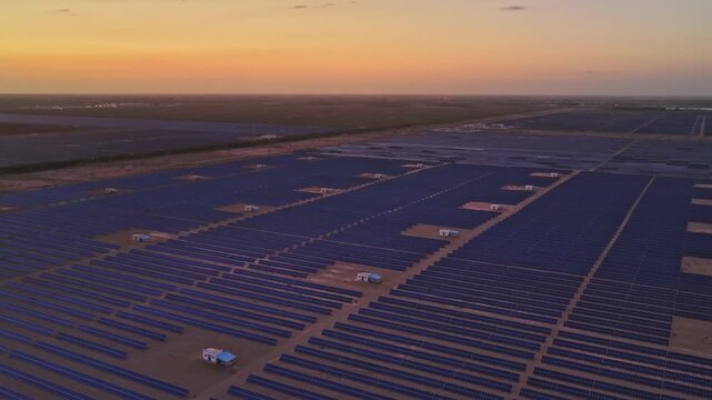 Solar photovoltaic panels at sunrise/sunset; wind turbine power plant; new energy