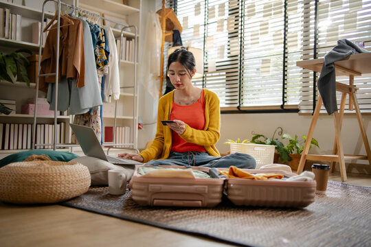 Asian woman using credit card for online hotel booking platform on laptop, representing creative professional women travel payment transaction, e-commerce shopping and holiday planning