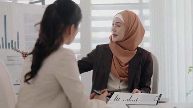 Two business colleagues multiethnic working in office, asian muslim