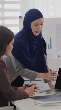 Two business colleagues multiethnic working in office, asian muslim