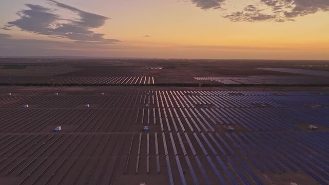 Solar photovoltaic panels at sunrise/sunset; wind turbine power plant; new energy