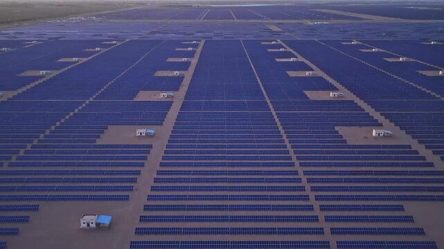 Solar photovoltaic panels at sunrise/sunset; wind turbine power plant; new energy