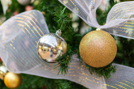 Golden glitter Christmas ball hanging on pine tree branch with bokeh background