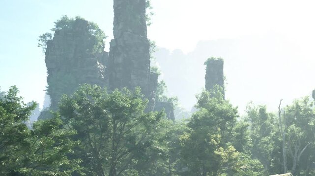 Tall rock formations rise above trees in a lush setting during early morning. Mist covers the landscape, creating a soft and muted atmosphere around the rocks.