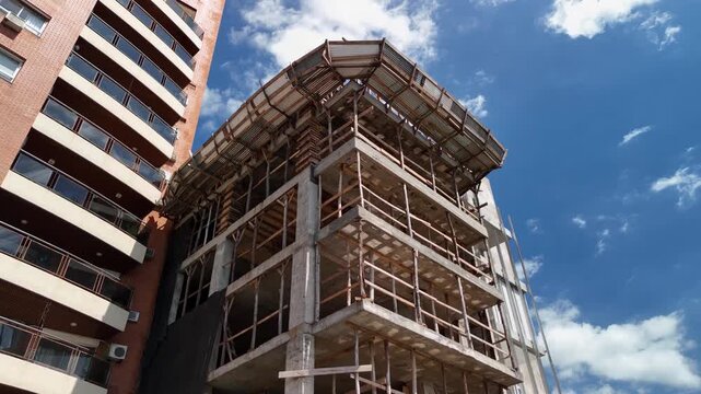Dynamic low-angle video capturing construction of modern residential building with blue sky background.