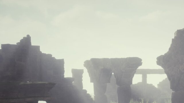 Ruins are visible shrouded in fog. Tall stone structures are outlined against the light sky. The ground is covered in grass around the ancient remains. Morning light enhances the scene.