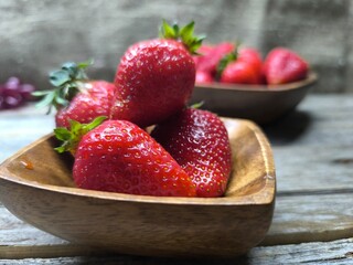Ripe sweet strawberries in a wooden plate on a wooden © nicolas
