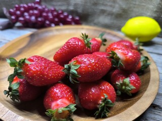 Ripe sweet strawberries in a wooden plate on a wooden © nicolas