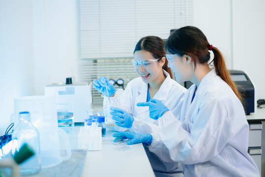 Asian female scientist holding a test tube with liquid sample during scientific research in a modern biotechnology laboratory.