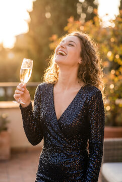 Middle aged woman celebrating champagne sequin dress sunset outdoor