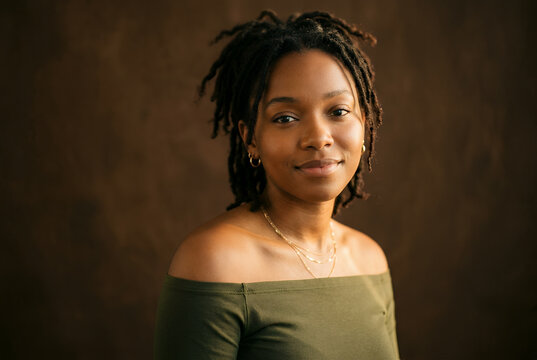 African American young woman smiling at camera with brown background