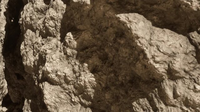A close view of a rock surface shows different textures and colors under natural light. The rock has cracks and uneven areas that create an interesting pattern.