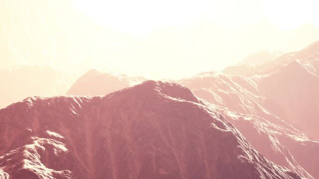 Bright sunlight shines over mountains with soft terrain features during daytime hours. The landscape appears warm and inviting, showcasing natural beauty and vastness in the scenery.