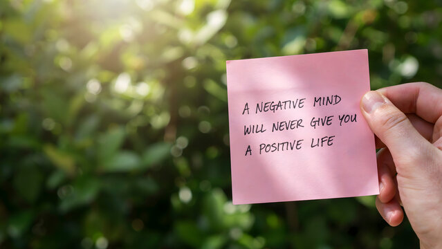 A person holding a pink sticky note with a motivational quote about life