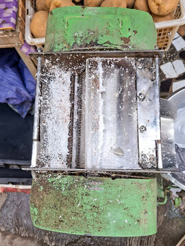 top-down view of an industrial metal grater blade coated with finely shredded white coconut residue.