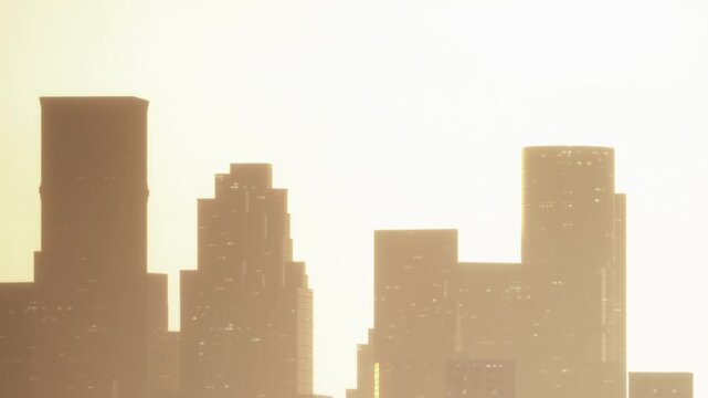 Silhouettes of tall buildings are visible against a bright sunset sky. The image shows the city skyline with strong outlines. The setting sun creates a warm glow.