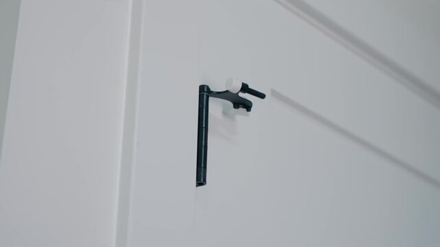 Slow motion handheld shot of black door stopper hardware mounted to a white interior closet door