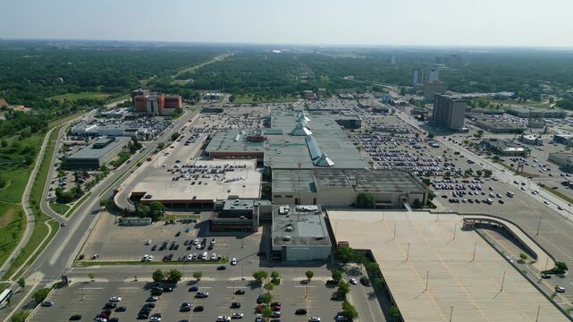 Aerial drone orbit of CF Polo Park showcasing the entire shopping centre, surrounding commercial district, roadways, and parking areas on a bright summer day