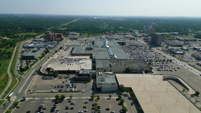 Aerial drone orbit timelapse of CF Polo Park shopping centre with heavy traffic, vehicle movement, and commercial activity on a bright summer day in Winnipeg, Manitoba