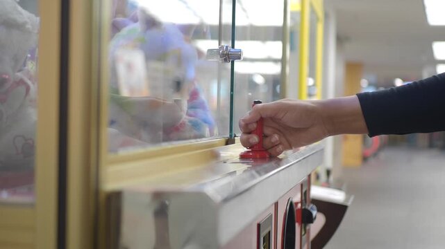 Playing with a claw machine in an arcade