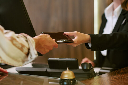 Close up of Caucasian female receptionist receiving passport from guest at hotel reception desk, representing check in process. Image ideal for hospitality and travel marketing
