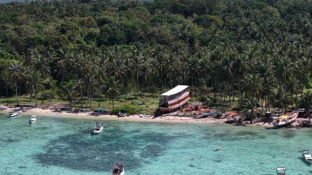 Aerial drone view of Barakuda Beach in Karimunjawa, Indonesia, showcasing white sand, turquoise water, tropical coastline, and lush coconut trees.