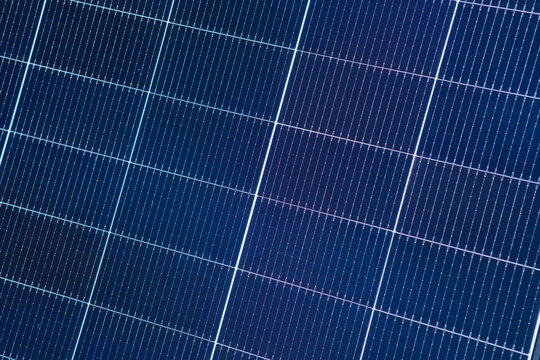 Close up of a solar panel grid with dark blue cells and white lines
