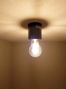 Warm LED light bulb on ceiling fixture in simple interior