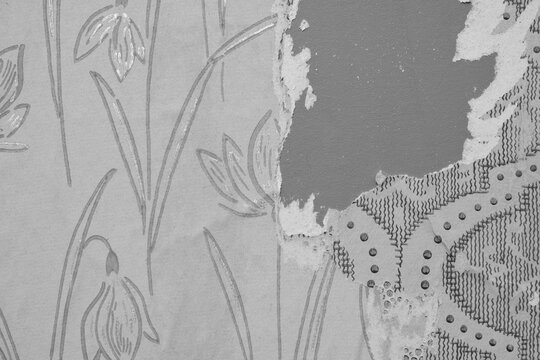 Old torn wallpaper layers on the wall, black and white.