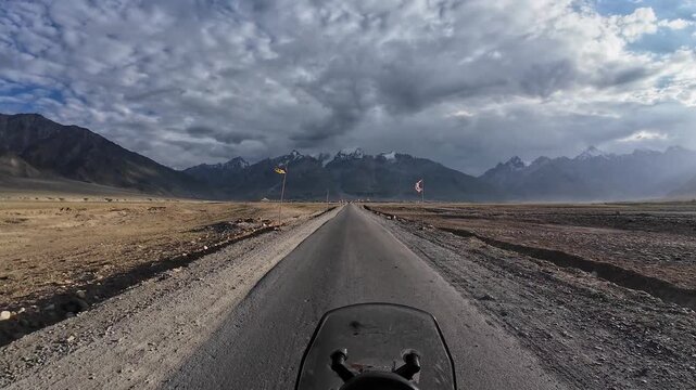 Padum, India : Point of view footage of motorcyclist ride on the asphalt road of Padum, high-altitude mountain road in Ladakh of India under dramatic cloudy sunset sky