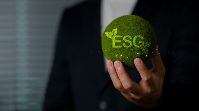 A professional individual holding a moss-covered sphere with the acronym ESG, representing environmental, social, and governance priorities in sustainability efforts.