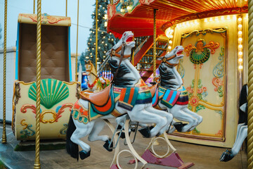 Vibrant traditional carousel horses and carriage on a vintage amusement park ride outdoors © reddish
