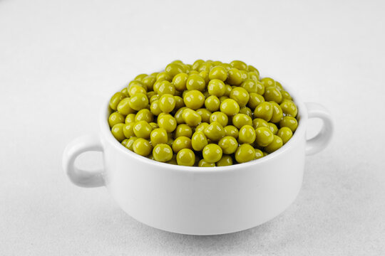 Green peas in white bowl  on bright background for clean eating, vegan food or healthy side dish concept