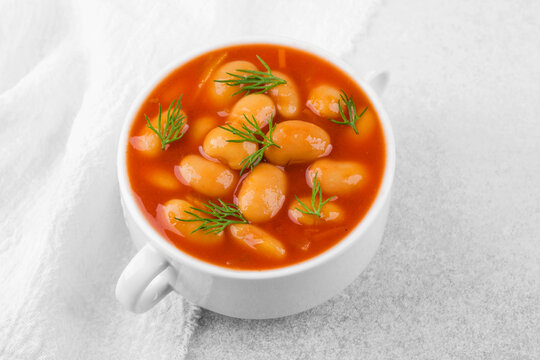 Cooked white butter beans with dill in bowl on white background for clean eating, vegan cooking or healthy food concept