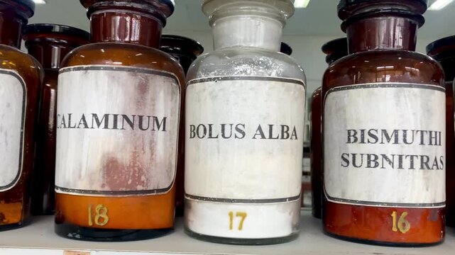 vintage apothecary glass jars with latin chemical labels on shelf