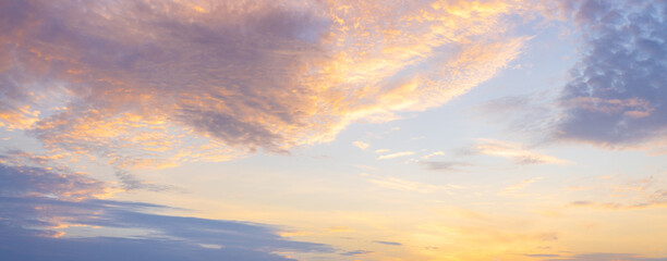 Obraz premium Golden Sunset Sky with Soft Clouds and Dramatic Atmosphere,A stunning view of a dramatic golden sunset sky filled with soft, textured clouds, radiating warm and peaceful light across the horizon.