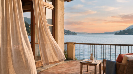 Fototapeta premium Balcony view of serene lake at sunset with sheer curtains gently blowing
