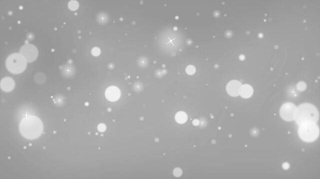Glowing bokeh circles and soft light particles float against a monochromatic grey gradient background.