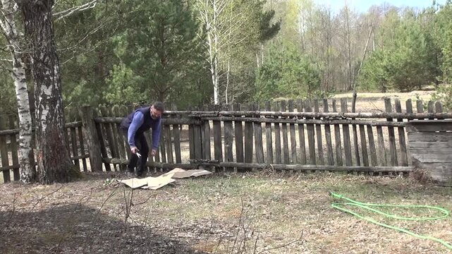 No-dig garden bed preparation. Man preparing a new garden bed using the layered cake method. Laying cardboard on the ground. Wide shot.