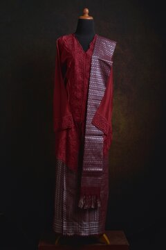 Maroon embroidered kebaya with songket skirt and shawl displayed on a dress form