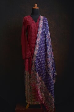 Maroon embroidered kebaya with batik skirt and shawl displayed on a dress form