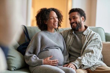 Obraz premium Pregnant woman and her partner smiling during a prenatal counselling session, sitting on a soft sage green sofa for partner support and wellness