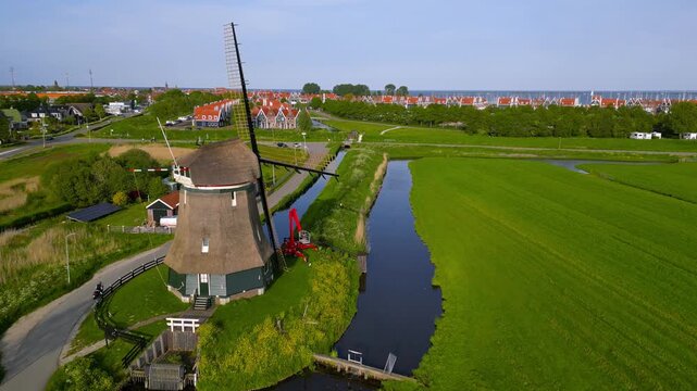 Traditional dutch windmill in a green landscape near Volendam.